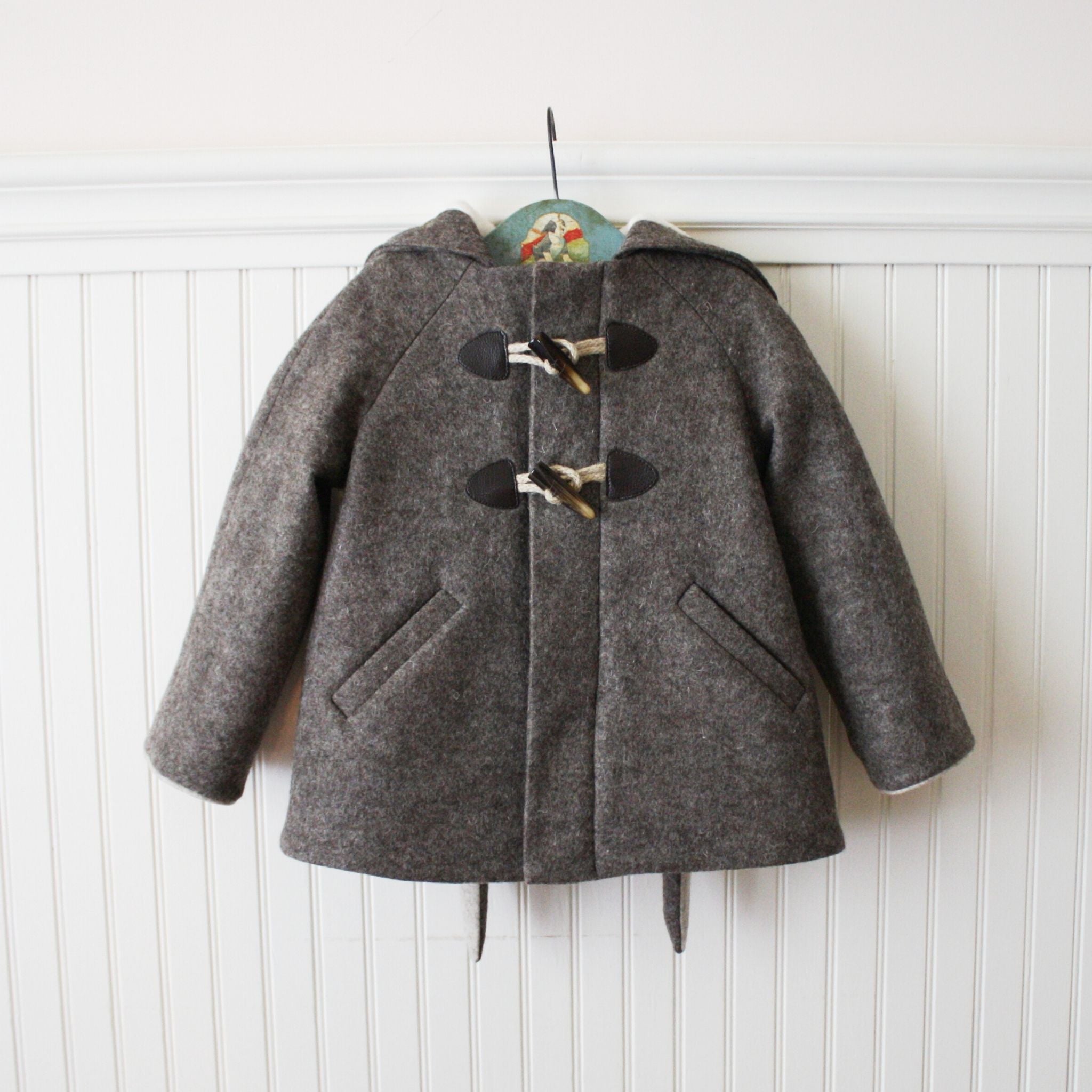 Front view of the Little Goodall Flopsy Bunny coat, featuring cozy wool fabric, toggle closures, hidden buttons, and functional welt pockets