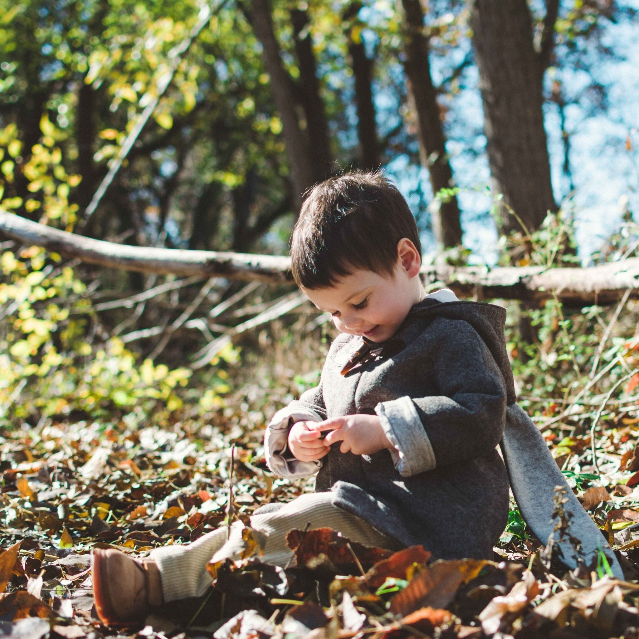 Child wearing Little Goodall Flopsy Bunny coat in a forest, featuring soft wool, plush lining, toggle closures, and bunny ear hood for warmth