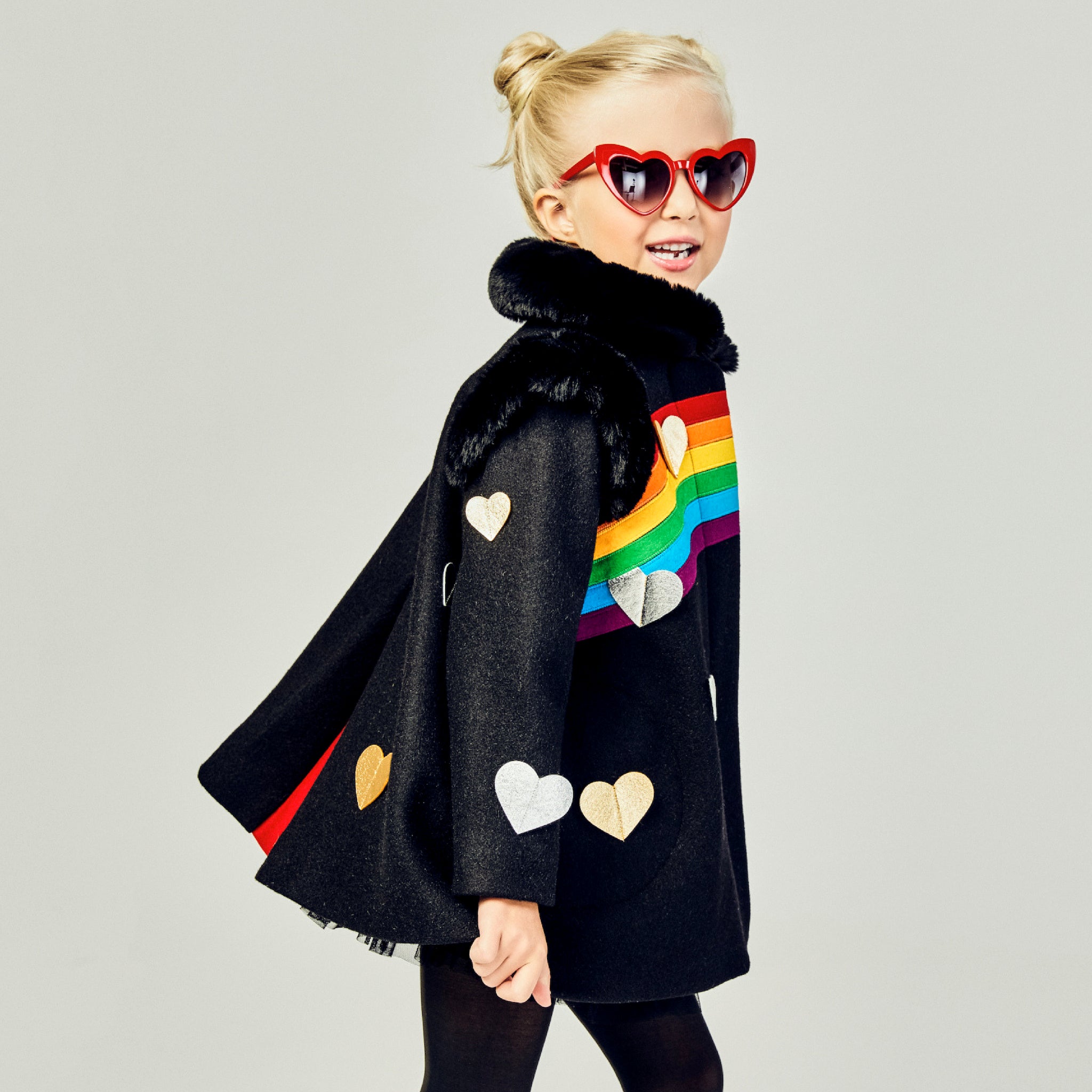 Girls' black wool coat with rainbow appliqué, gold and silver hearts, faux fur collar, and red pleat detail