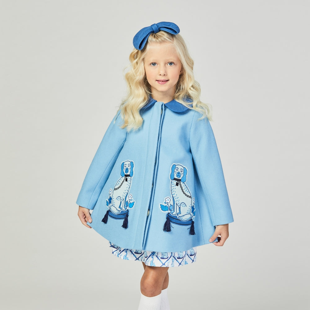 Girl wearing the Aldrich and Madame De Bleu coat, a light blue wool coat with embroidered Staffordshire dogs, tasseled details, and a Peter Pan collar