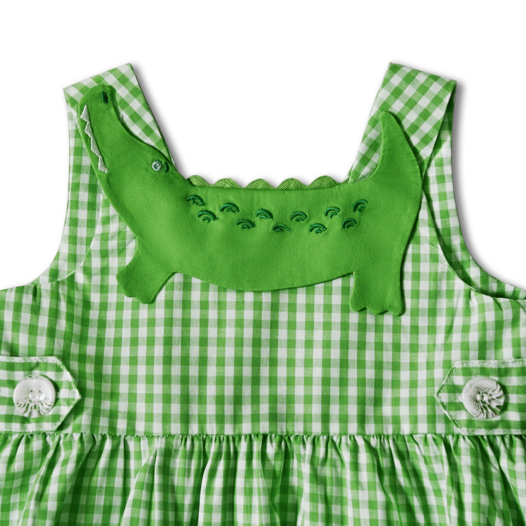Close-up of green gingham sundress featuring an embroidered alligator applique on the bodice