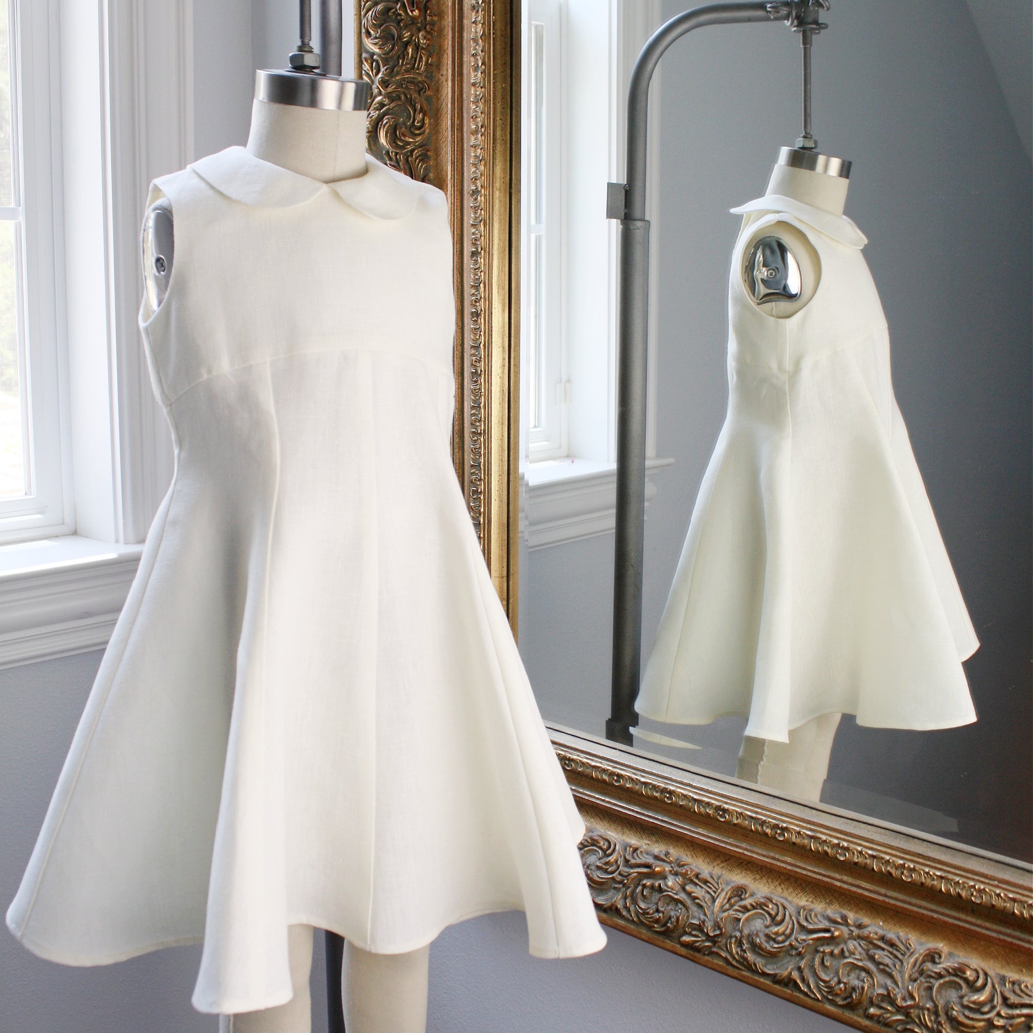 A beautifully designed ivory linen dress for girls, perfect as an heirloom piece, with a structured silhouette and classic Peter Pan collar.