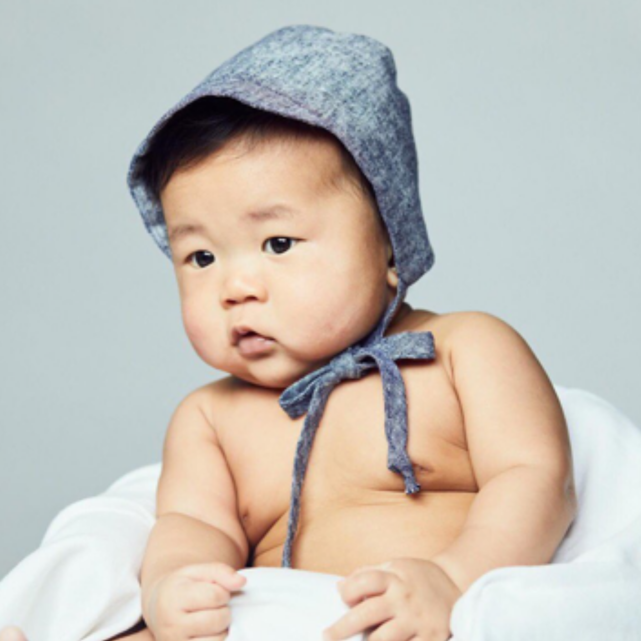 Baby wearing an indigo linen bonnet with a visor for sun protection.