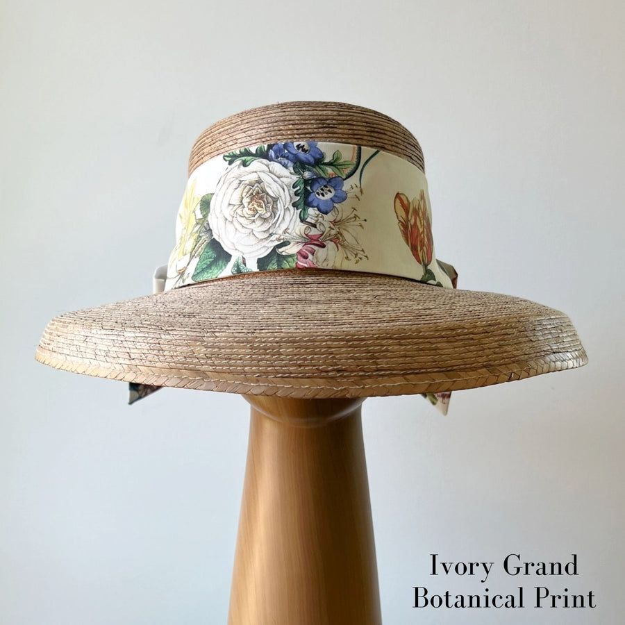 Front view of ivory floral Middy Bow hatband on straw sun hat, featuring wide ribbon with colorful botanical print