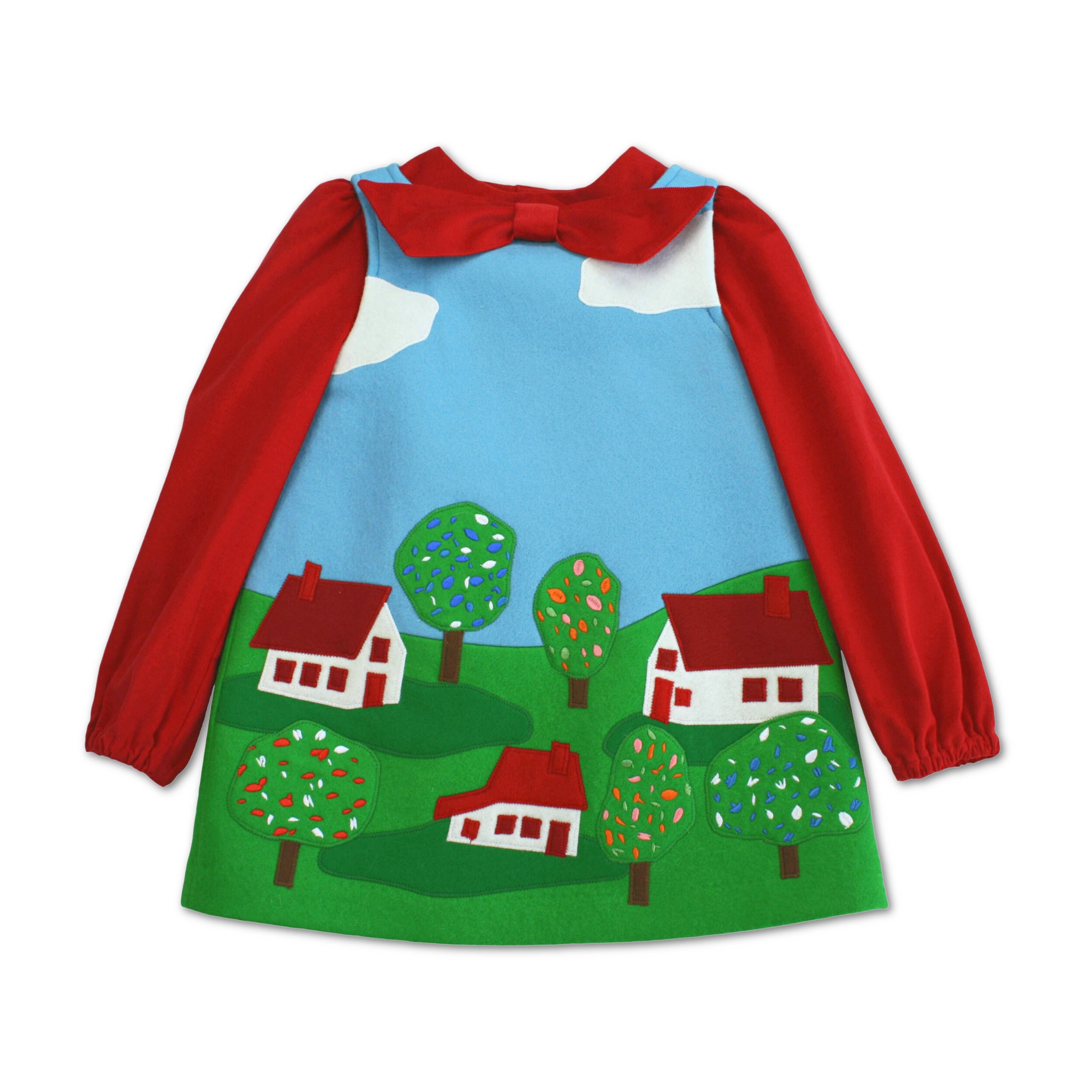 Flat-lay of the Little Cloud Dress with a red bow blouse, featuring appliqued houses and embroidered trees.