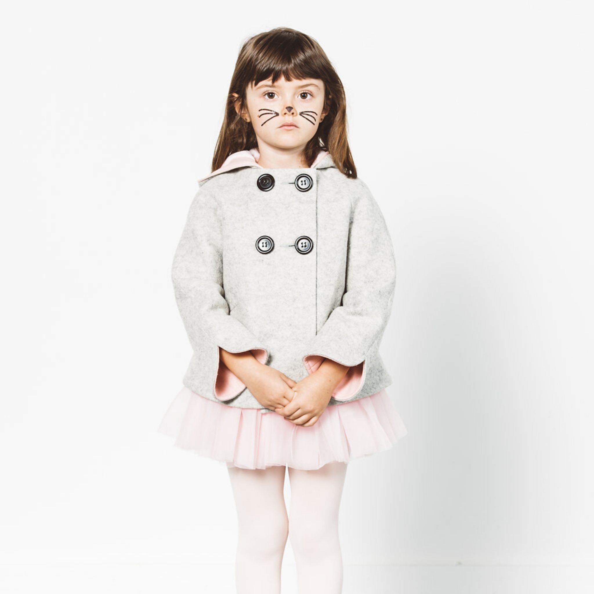 Girl wears a grey bunny coat with pink-lined cuffs, a cozy hood, and double-breasted buttons, styled with a pink tutu and tights.