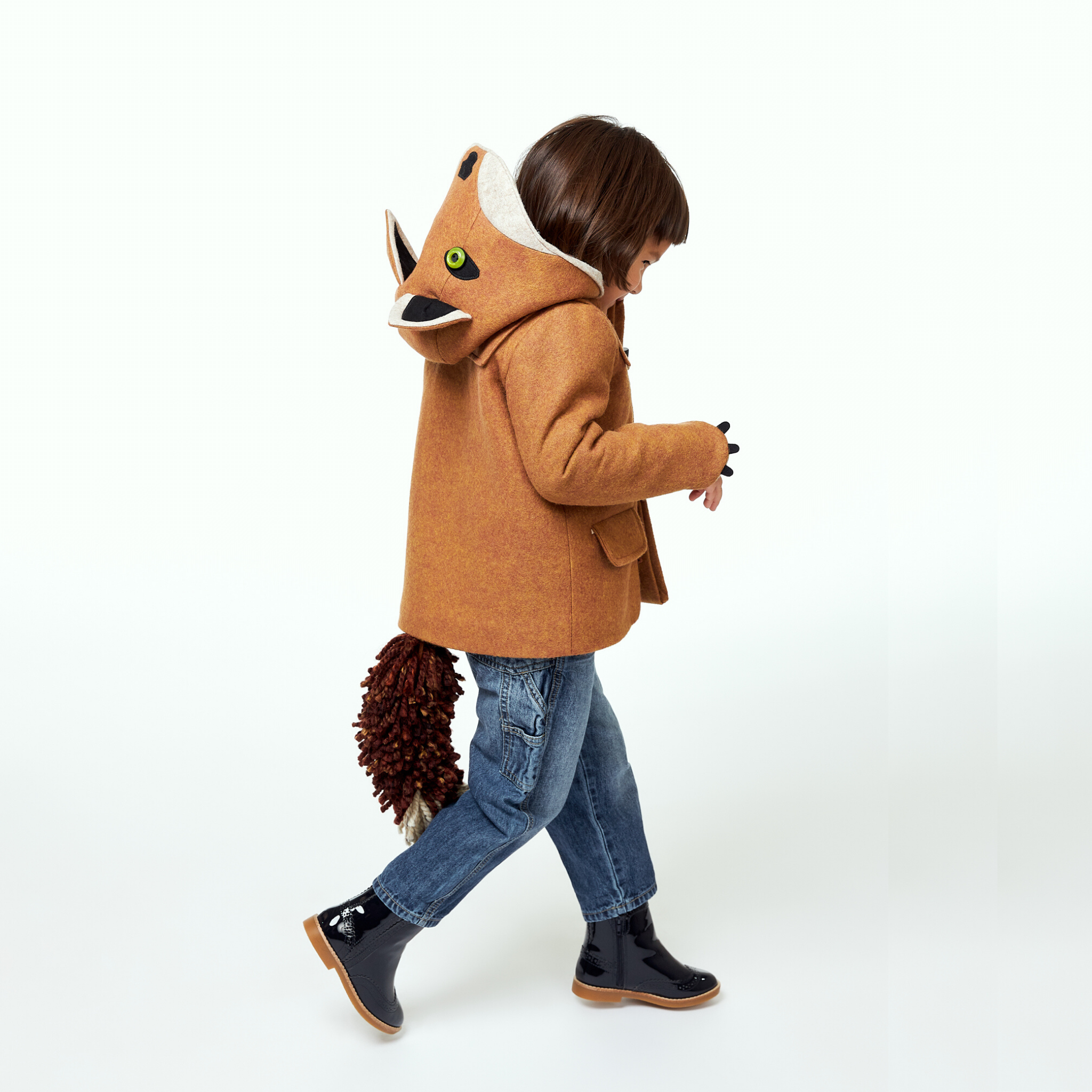 Child walking in a wool fox coat with a hood featuring fox ears and a detachable tail