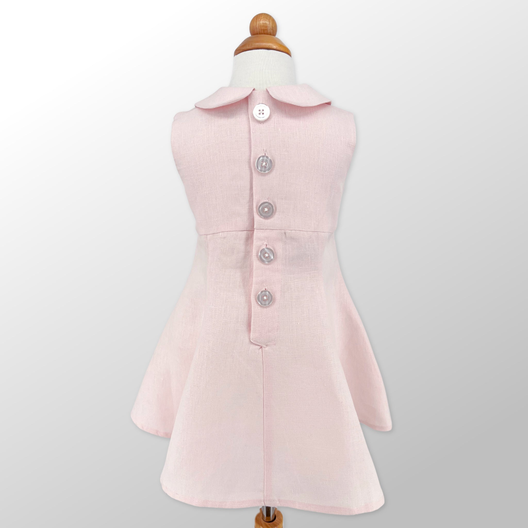 Back view of Little Goodall Blush Linen Scooter Bunny Dress, featuring elegant button closure and tailored fit