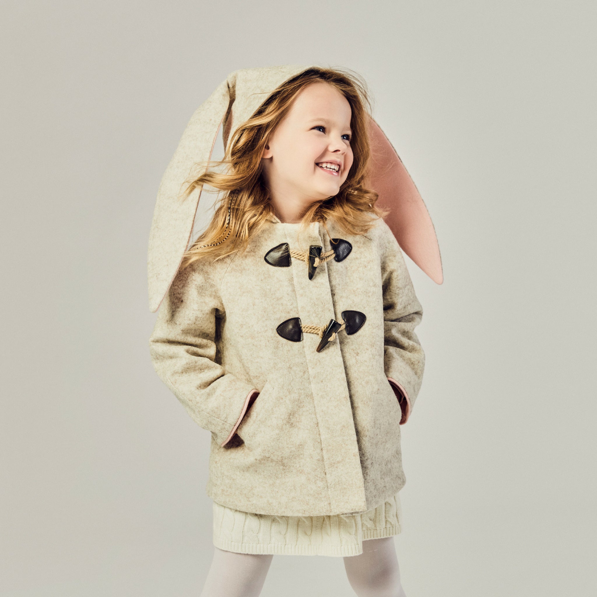 Toddler girl wearing a Merino wool Snowshoe Rabbit Coat with floppy bunny ears and toggle closures