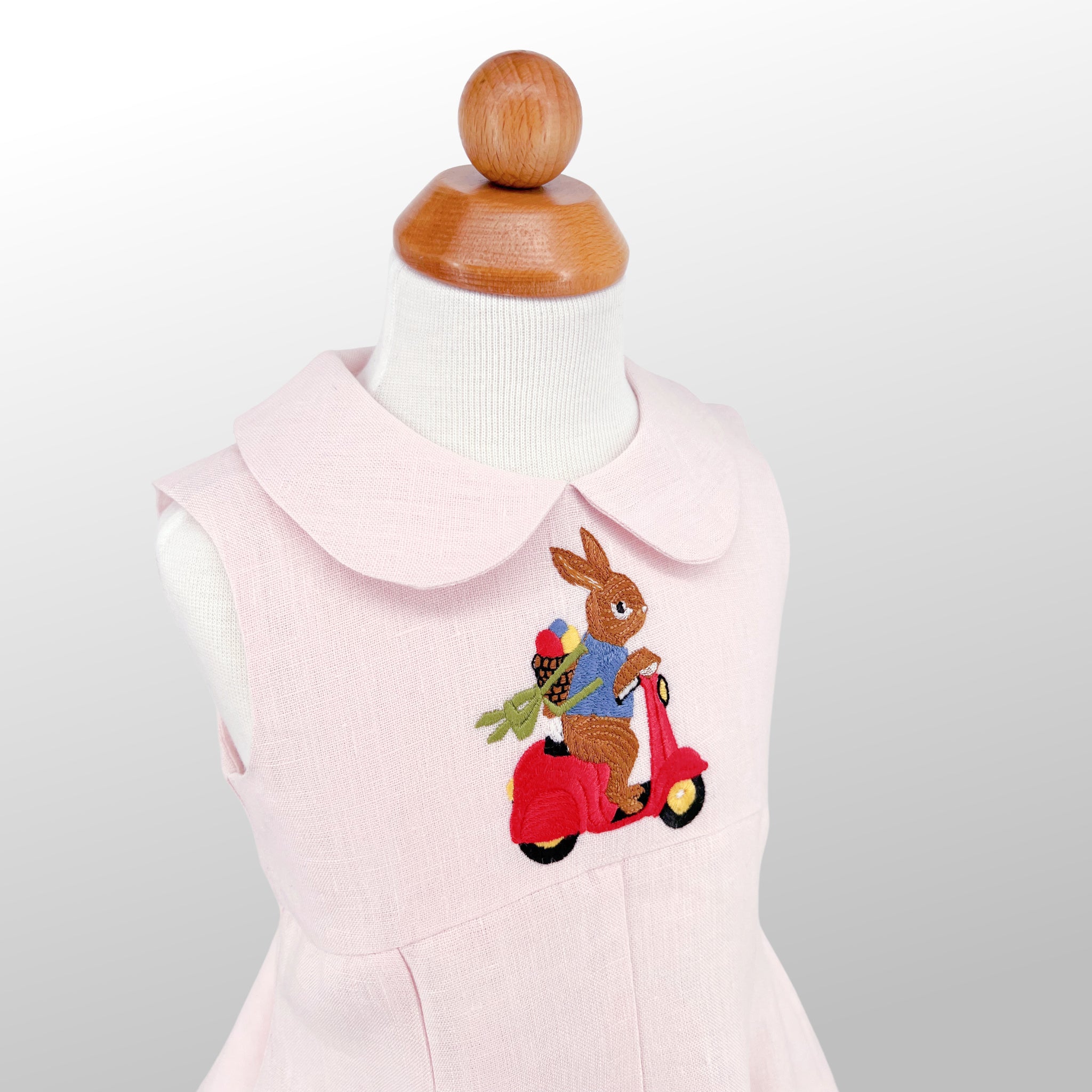 Charming pink linen dress for girls, featuring an embroidered bunny on a scooter. A perfect heirloom-quality outfit for summer time festivities