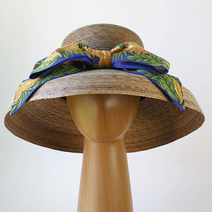 Rear angled view of Audrey Sunflower straw hat highlighting wide brim and French blue embroidered bow