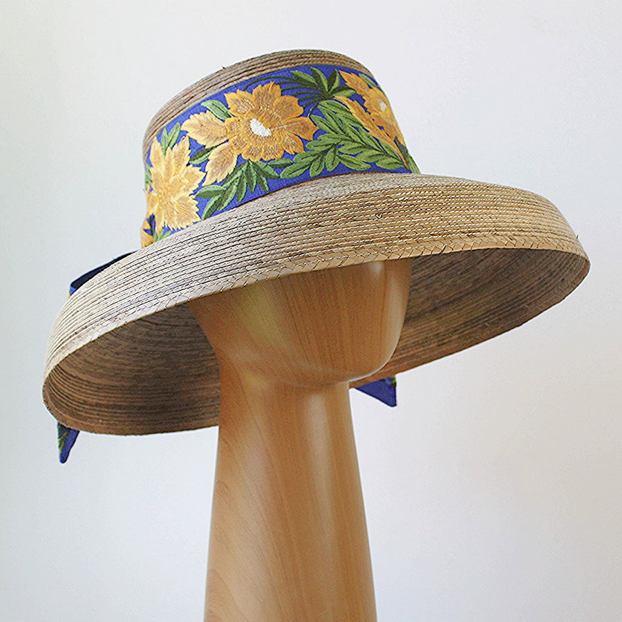 Side view of Audrey Sunflower straw hat with French blue band and yellow floral embroidery on natural wide brim