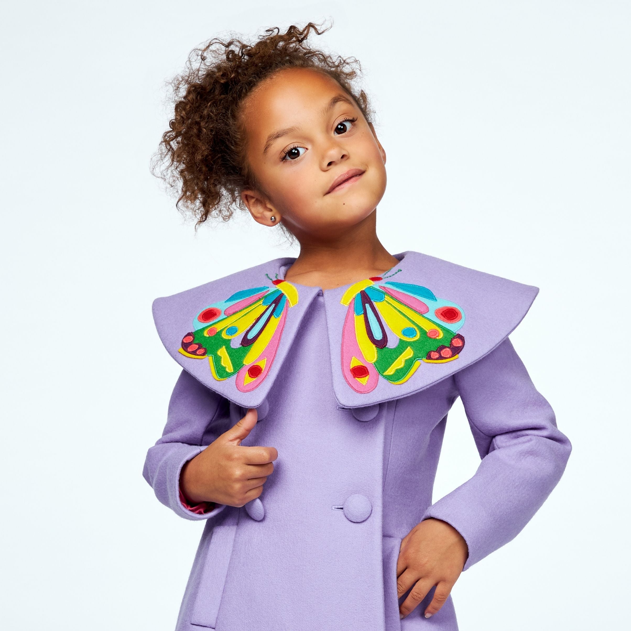 Close-up of a young girl in a purple wool coat with a bold butterfly collar, double-breasted buttons, and colorful embroidery