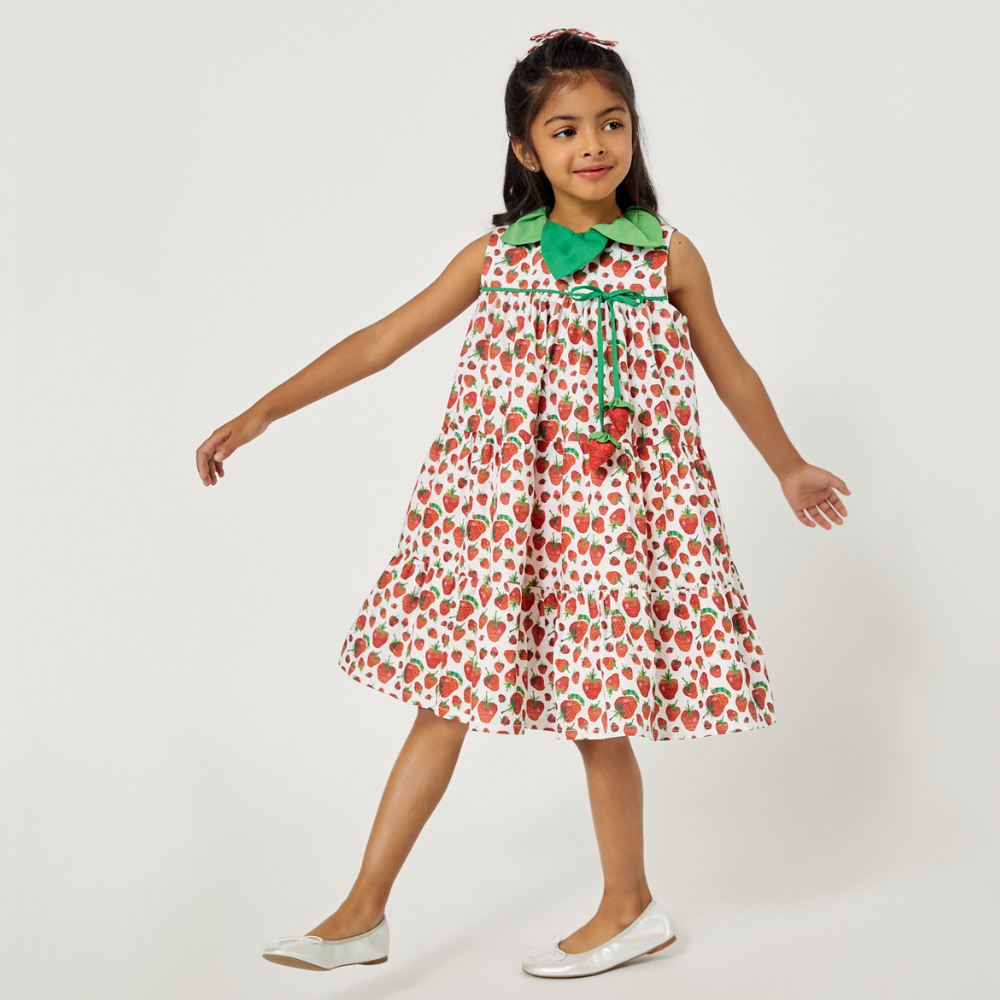 Girl spinning in a sleeveless strawberry dress with a green collar and playful strawberry accents