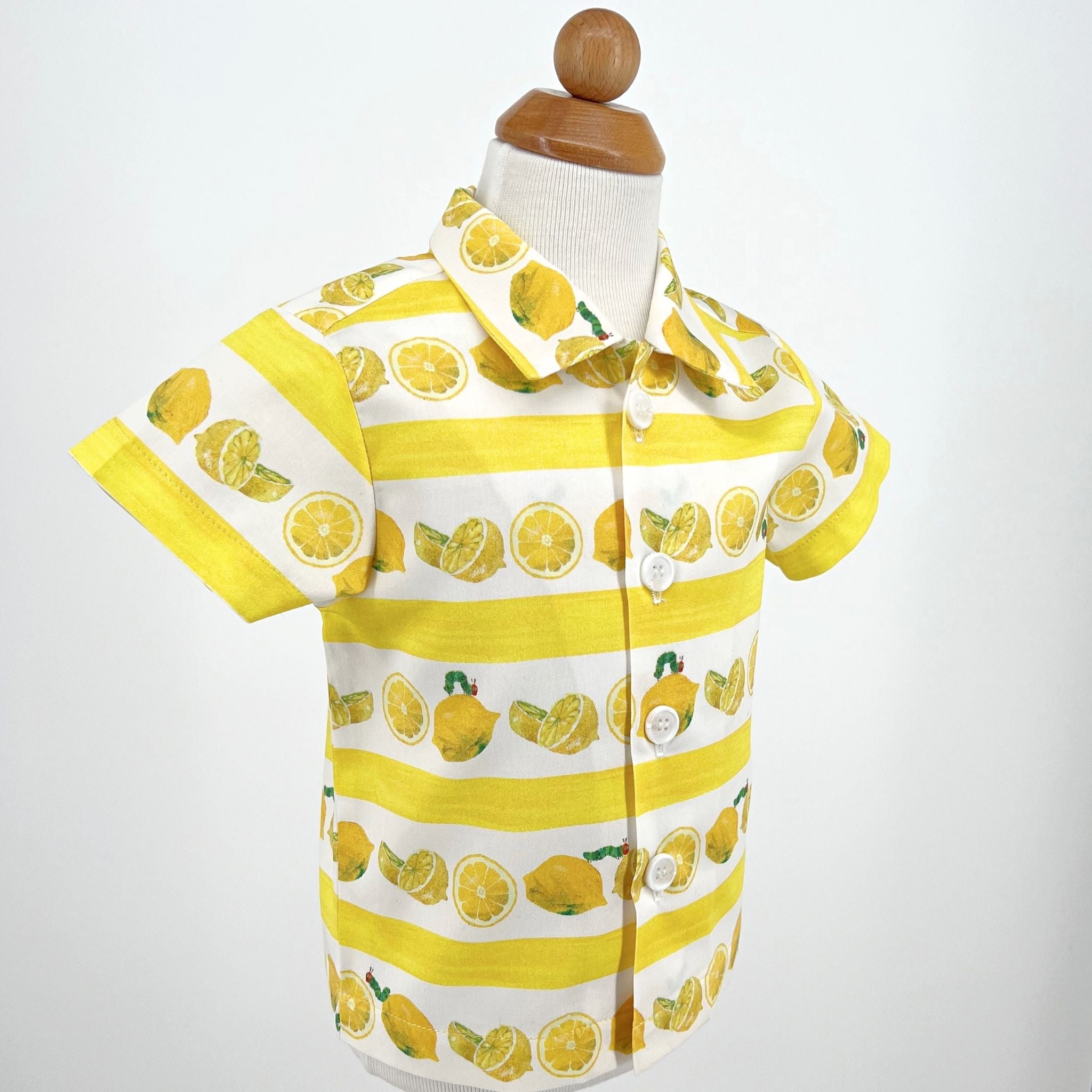 Close-up of boys' lemon print short-sleeve button-up shirt with striped yellow and white design