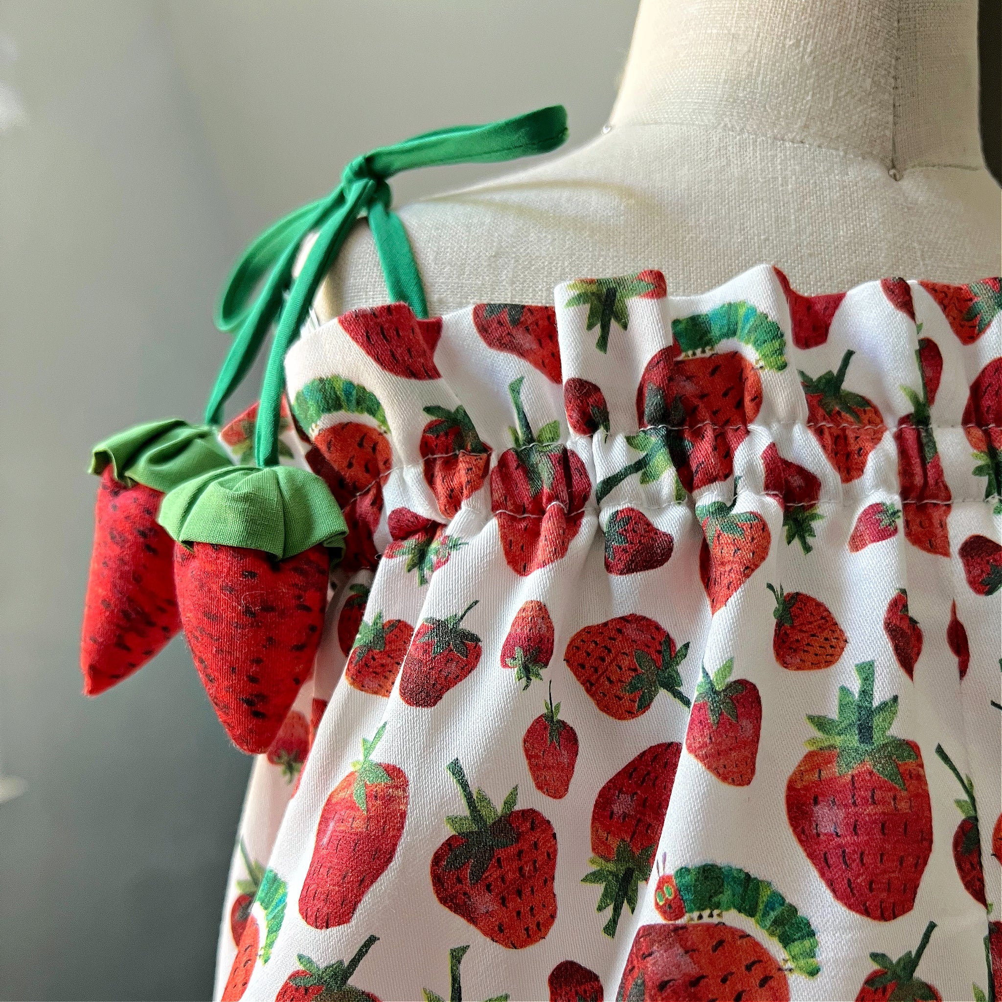 Close-up of strawberry bubble romper with tie-shoulder straps and plush strawberry accents