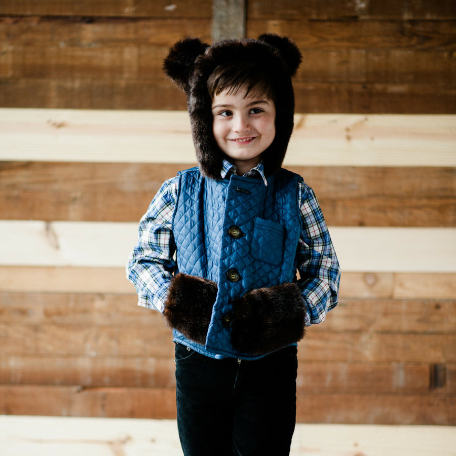 Boy wearing a blue quilted bear vest with faux fur ears and mittens, part of the Wild Things to Sew and Wear collection. Cozy and playful design